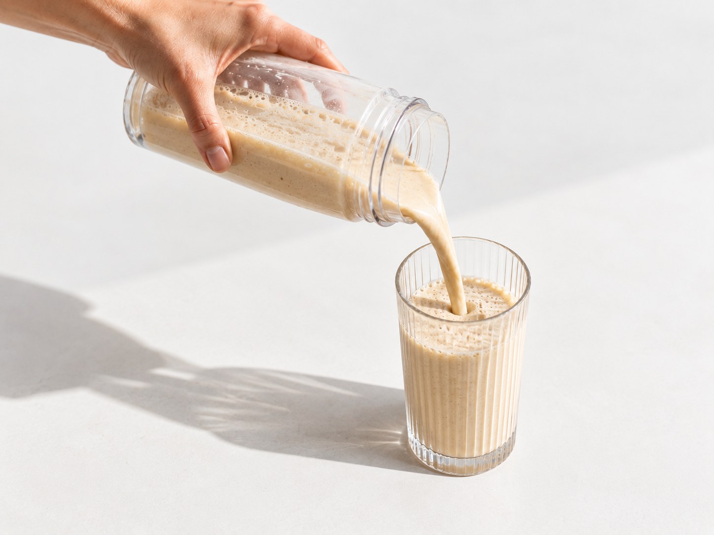 Pouring a prepared Powerlogy Whey Protein Coconut & Almond shake into a glass