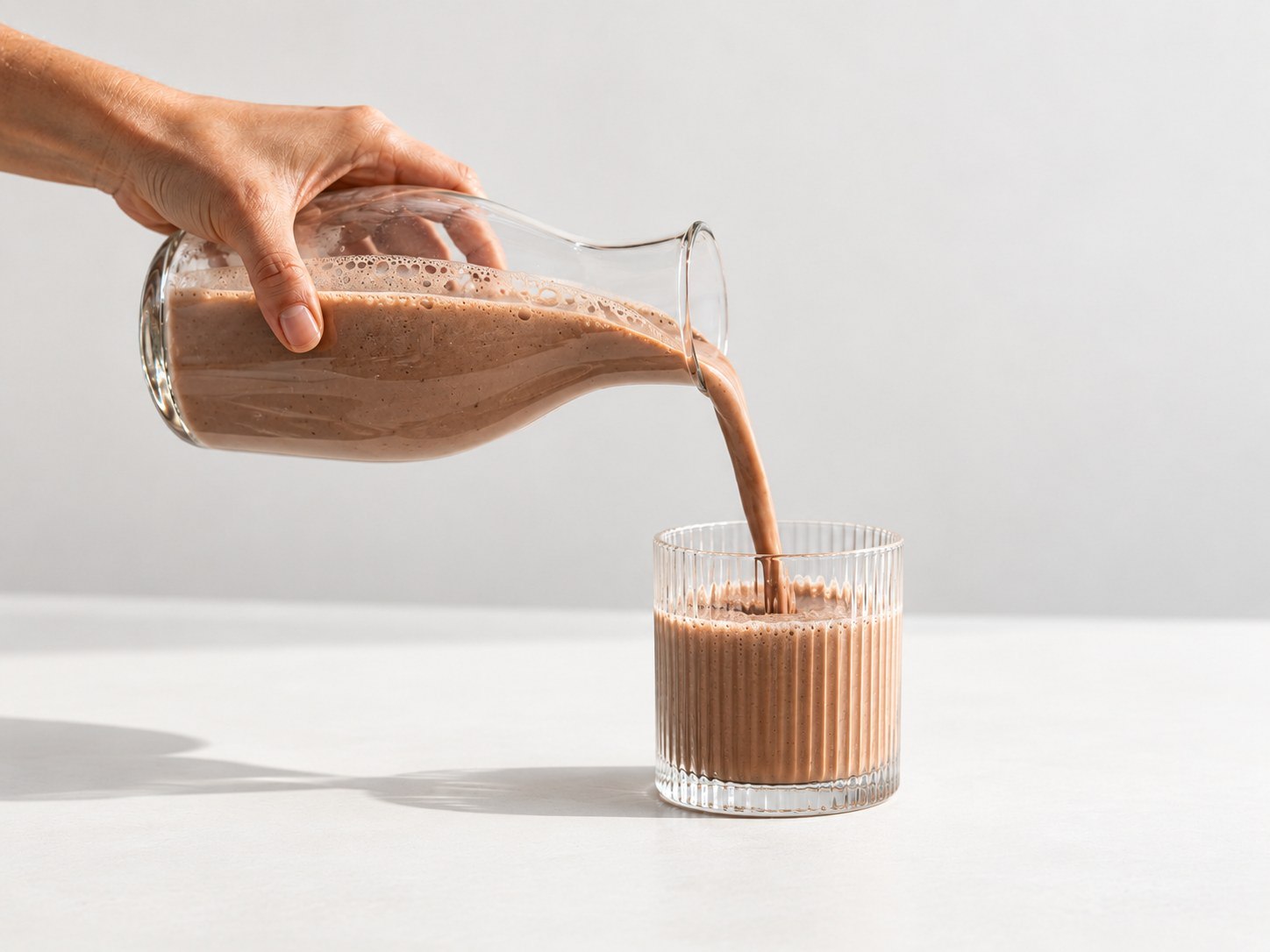 Der fertige Powerlogy Whey Protein Dark Chocolate Shake wird ins Glas gegossen