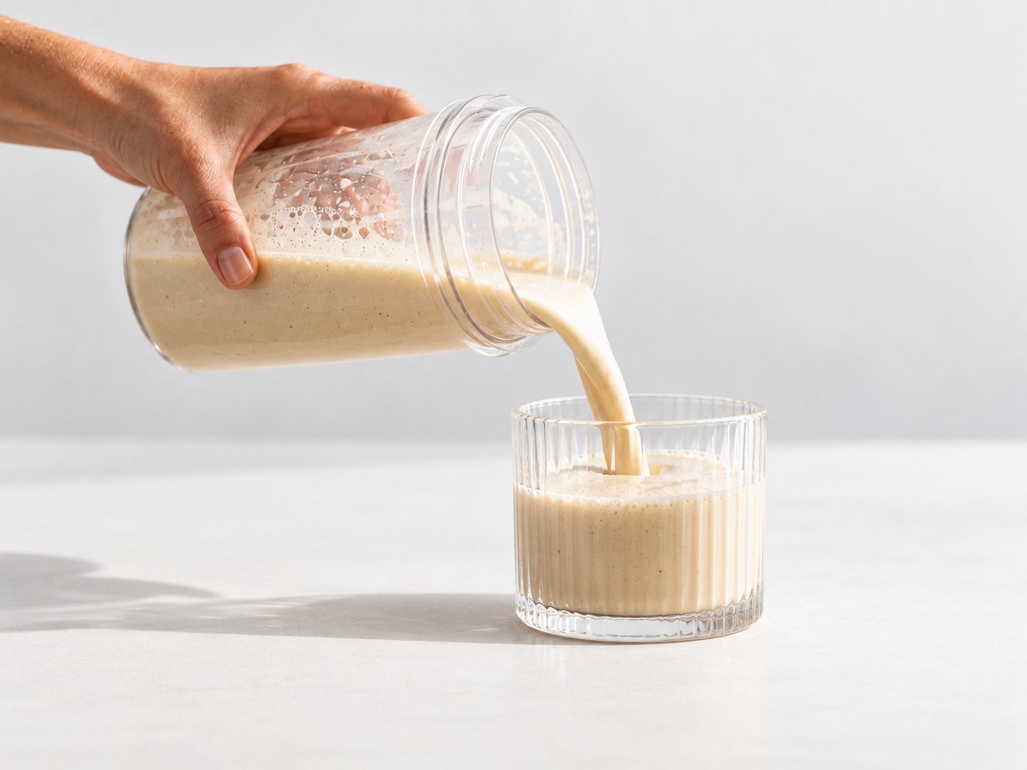 Nalievanie pripraveného proteínového nápoja Powerlogy Upgraded Vegan Protein do pohára