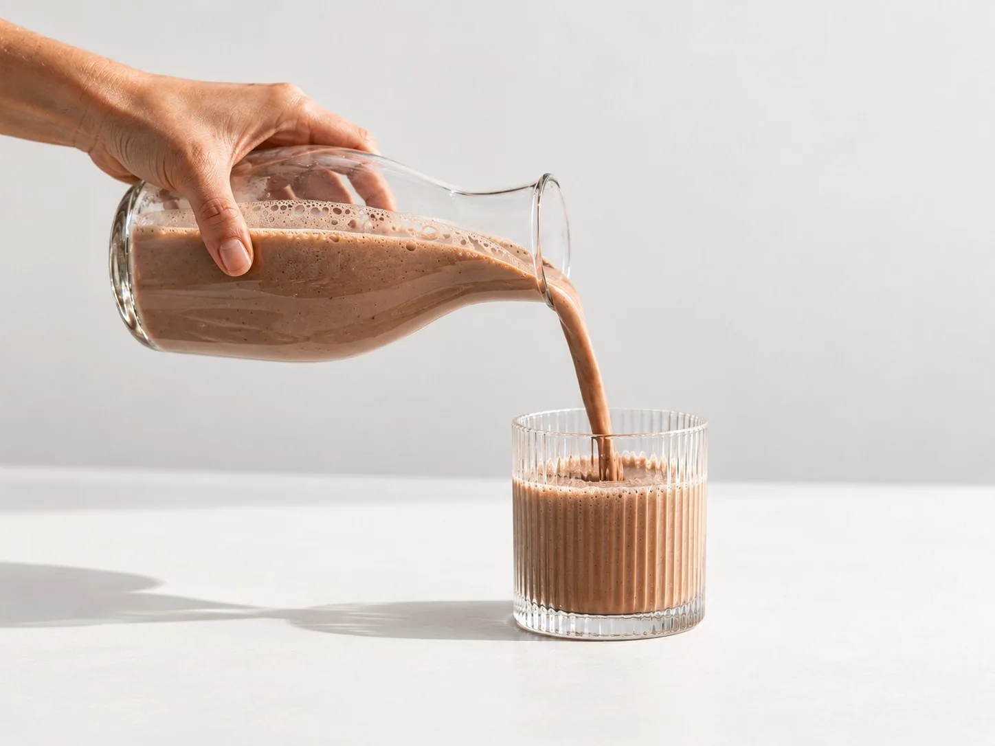 Der fertige Powerlogy Whey Protein Dark Chocolate Shake wird ins Glas gegossen
