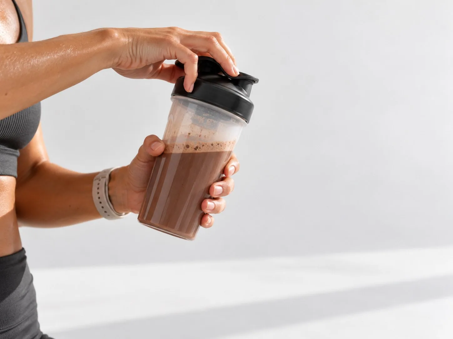 Preparing a Powerlogy Upgraded Sport Protein Dark Chocolate shake in a shaker after a workout